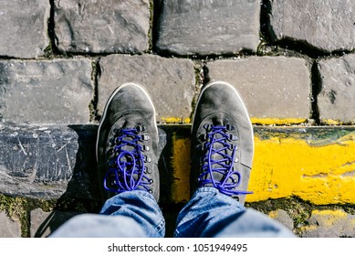 Reaching a crossroads having to decide about past, now and future symbolized by two feet and shoes standing on two different pathway material from above