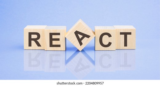 REACT Word Written On Wood Block. Blue Background. Business Concept. Inscription On The Cubes Is Reflected From The Surface Of The Table. A Color Gradient Is Used.