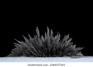 A reaction of iron dust to a magnetic field of a strong neodymium magnet on a black background