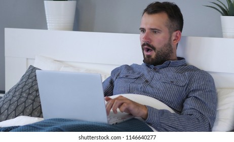 Reaction of Loss by Sad Man Using Laptop in Bed - Powered by Shutterstock