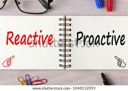 Reactive or Proactive written on notebook on wooden desk with marker pen and glasses.Business Concept.Top view.
