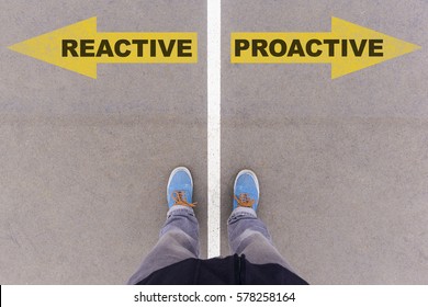 Reactive vs Proactive text on yellow arrows on asphalt ground, feet and shoes on floor, personal perspective footsie concept