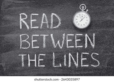 read between the lines phrase written on chalkboard with vintage precise stopwatch 