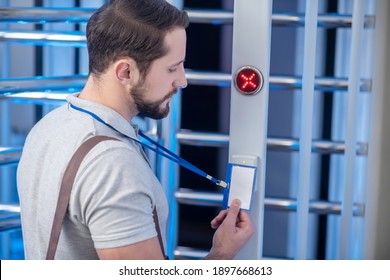 Reader Device. Dark-haired Young Bearded Man In Profile Applying His Badge To Reader On Turnstile