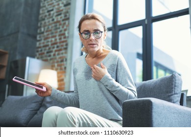 Reading Away. Low Angle Of Restless Mature Woman Holding Tablet And Having Hot Flash