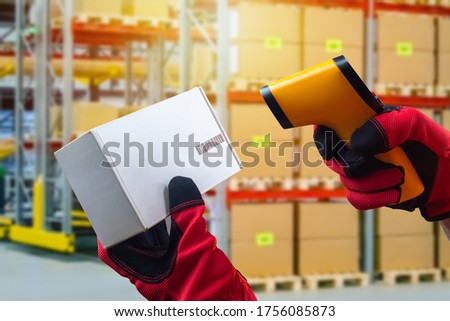 Reading a barcode from a cardboard box. Hands in work gloves hold a barcode reader and a box. Acceptance of goods to the warehouse. Product encoding.