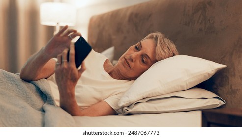 Reading, bed and mature woman with cellphone for online blog on insomnia, sleep apnea or relaxing. Communication, night and senior female person networking with email on phone in bedroom at home. - Powered by Shutterstock