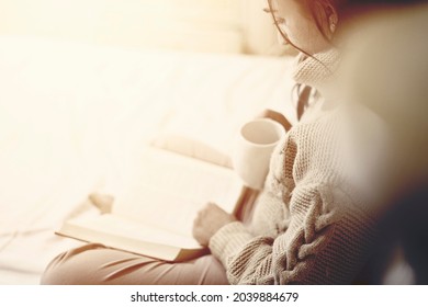 Lesen im Bett. Junge Frau trinkt Kaffee und liest ein Buch im Bett. Eine Frau mit mehreren Rassen liest ein Buch im Bett. Gemütlicher Herbstmorgen im Schlafzimmer. Junge Frauen genießen Wochenende