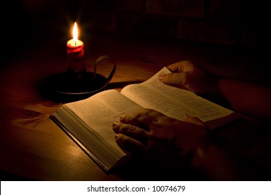 Reading The Bible By Candle Light. Only Light In This Image Is From The Candle. Perfect For Religious, Eater Or Christmas Themes.