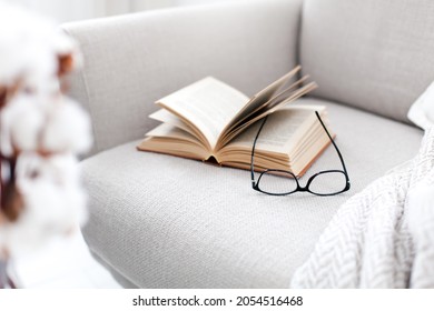 Reading book at home. Opened paper pages and spectacles on couch - Powered by Shutterstock