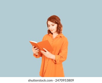 Reading book, portrait of side view young caucasian red bob hair woman reading book. Learning new information, holding hands. Isolated blue background. Copy space. Wear orange shirt. - Powered by Shutterstock