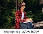Reading the book using Braille technique. Blind young guy is in the town outdoors.