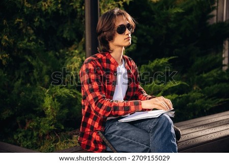 Reading the book using Braille technique. Blind young guy is in the town outdoors.