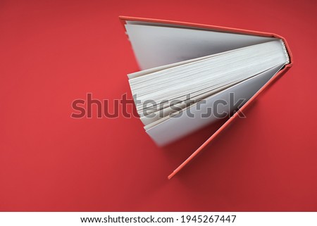 Reading books concept.Learning and knowledge concept. Book with a red cover on a red background.books close up. Book pages macro.top view, copy space