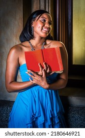 Reading By The Window. Young Black Woman, Holding Red Book, Standing By Window, Reading, Smiling.