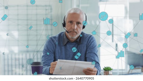 Reading consultant wearing headset and holding papers at office desk, with network icons. Corporate, professional, modern, digital, technology, workspace, collaboration
