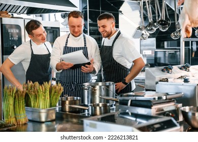 Reading the documents. Kitchen workers is together preparing the food.