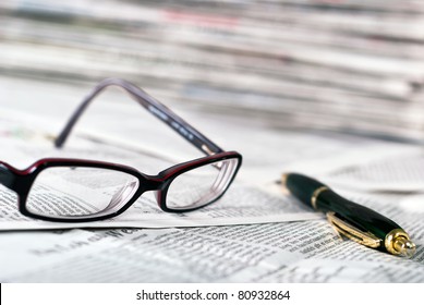 Reading Glasses And A Ballpoint Pen Lie On A Newspaper