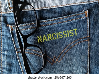Reading glasses in jeans pocket with yellow screen text NARCISSIST, means self-centered arrogant thinking and behavior, people who lack of empathy for others, excessive need of admiration 