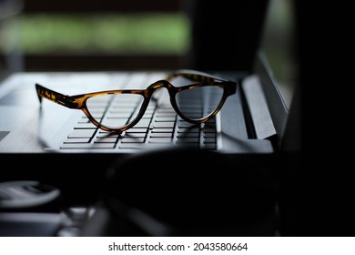 Reading Glasses On Laptop Keyboard In Low Light Background.