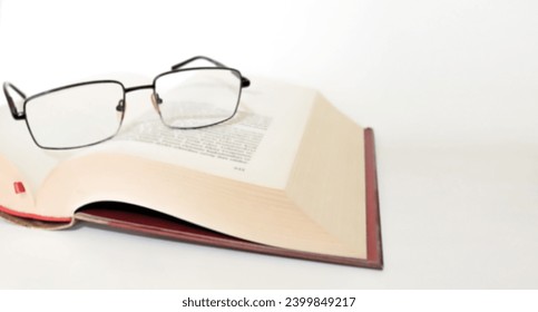 Reading glasses on open book page. Blurred background photo