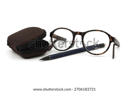 Reading glasses with tortoiseshell frames, pen and colorful red thumb tack over a white background with copy space in a business still life