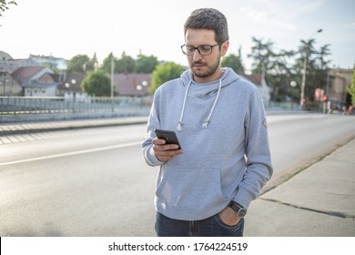 Reading Local News On Phone - Man Using Smartphone On City Street, Outdoor Shoot, Back Light