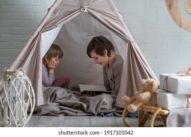 Reading nook. Two cute brothers reading a bedtime story in play room. Cozy room for kids in scandinavian style - Shutterstock ID 1917101042