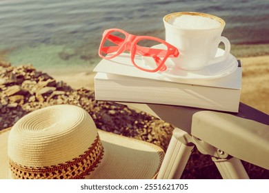 Reading on holidays. Coffee cup and book on chair outdoors against blue sea water background. - Powered by Shutterstock