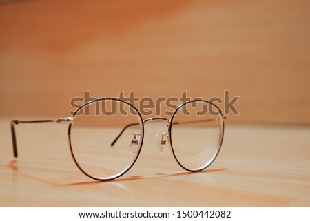 Reading thin frame glasses on wooden table. Vintage style with blur background.