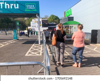 Reading, UK - April 15 2020: People Queue In A Car Park, Observing Social Distancing, To Enter A Supermarket During The Coronavirus Pandemic.