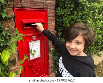 Reading, UK - July 16 2020: A Child Posts A Letter In A Postbox.