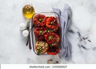 ready baked stuffed peppers in a glass baking dish on white marble table. healthy vegan cuisine for the whole family. comfort food