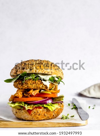 Ready to be served and eaten, freshly made vegan burger made of homemade chickpea patty, served with ketchup and mayo, lettuce, tomato, red onion, spinach, gherkin, micro herbs and kimchi. 