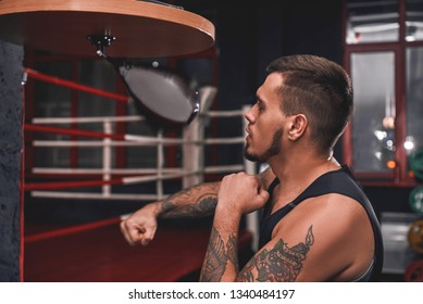 Ready to break his record. Close-up of muscular tattooed boxer in sports clothing hitting punching speed bag while exercising in boxing gym - Powered by Shutterstock