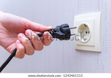 Ready to connect. Plugging electrical, black plug in electric socket on wall. 