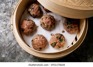 Ready to cook meatballs in asian bamboo steamer over a metal background. Top View. Flat Lay.