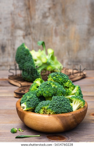 Ready to eat fresh raw broccoli is\
divided into inflorescences in a wooden plate on a wooden table.\
Healthy lifestyle, nutrition and zero waste\
concept