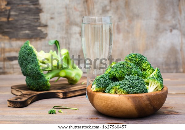 Ready to eat\
fresh raw broccoli is divided into inflorescences in a wooden plate\
and on a cutting board  on a wooden table. Healthy lifestyle,\
nutrition and zero waste\
concept