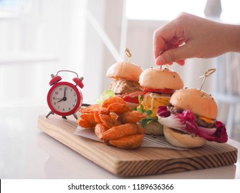 Ready to eat mini hamburgers and alarm clock on wooden tray. Fast Breakfast.    - Shutterstock ID 1189636366