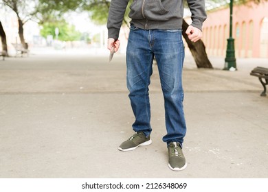 Ready To Fight. Young Man And Criminal Thief Holding A Knife On The Park While Waiting To Steal Money 