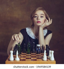 Ready for game. Young woman in art action isolated on brown background. Retro style, comparison of eras concept. Beautiful female model like legendary chess player, queen or duchess, old-fashioned.