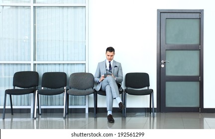 Ready for interview. Thoughtful  man in formalwear holding paper while sitting at the chair in waiting room 