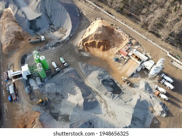 Ready mix concrete batching plant. Producing сoncrete and portland cement mortar for construction and formworks. Pouring concrete through to a ready-mixed truck. Drone view. Out of focus - Shutterstock ID 1948656325