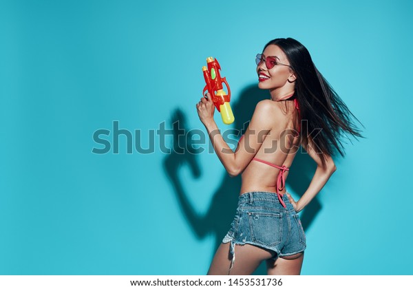 Ready to play.\
Attractive young Asian woman smiling and looking at camera while\
standing against blue\
background