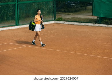 Ready to play. One young sportswoman, professional tennis player walking on clay court in bright summer day. Wide angle view. Concept of healhy lifestyle, action, motion, youth. - Powered by Shutterstock