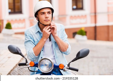 Ready to ride. Handsome young man wearing helmet while sitting on scooter  - Powered by Shutterstock