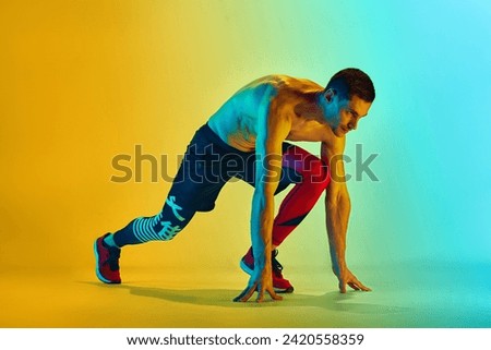 Ready to run. Muscular, sportive young man training shirtless against gradient blue yellow background in neon light. Concept of active and healthy lifestyle, sport, fitness, endurance