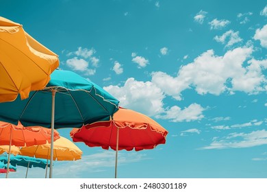 Ready for a Summer vacation. Colorful beach umbrellas against a blue cloudy sky - Powered by Shutterstock