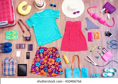 Ready For Travel. Overhead Of Essentials For Vacation. Top View Of Male And Female Summer Accessories, Clothes And Gadgets On The Wooden Background. Packing Suitcase.